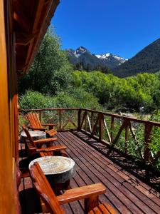 two tables and chairs on a deck with mountains at Rio Manso cabaña km 18 in Río Villegas +28 photos