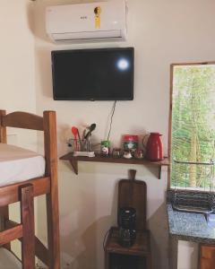 a room with a tv on a wall with a shelf at Village verde in Itacaré +27 photos
