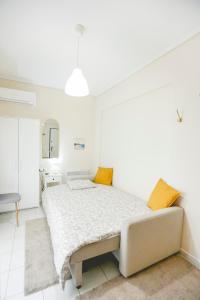 a white bedroom with a large bed with yellow pillows at Tiny Studio in Larisa