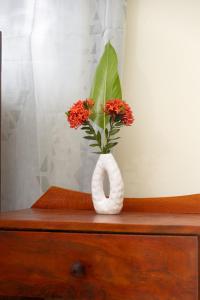 a white vase with flowers in it on a dresser at Happy Nest Dominica in Marigot