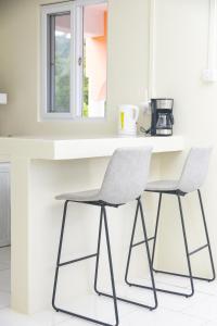 a kitchen with a white counter and two chairs at Happy Nest Dominica in Marigot