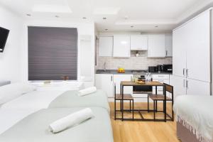 ein Schlafzimmer mit 2 Betten und eine Küche mit weißen Schränken in der Unterkunft Eurostar Budget Rooms - Next to Kings Cross & Eurostar Train Station in London + 20 Fotos