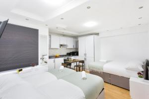 a hotel room with two beds and a kitchen at Eurostar Budget Rooms - Next to Kings Cross & Eurostar Train Station in London
