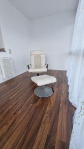 a chair and a stool in a room with wooden floors at Wohnen auf Zeit - perfekt für Grenzgänger, Wochenend-Heimkehrer und Berufsreisende in Schwörstadt +12 photos