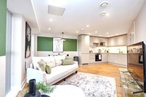 a living room with a white couch and a kitchen at Comfortable Leeds Flat - Ideal For Long Stays in Leeds