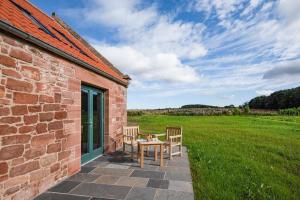 a patio with two chairs and a table on a brick building at Ploughman's Bothy at Papple Steading in East Linton