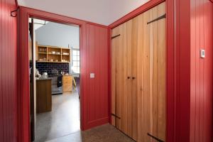 um quarto com paredes vermelhas e uma porta vermelha em Ploughman's Bothy at Papple Steading em East Linton