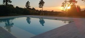 a swimming pool with the sunset in the background at Glamping Podere Poggiagrilli in San Gervasio