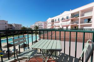 - un balcon avec une table et des chaises à côté de la piscine dans l'établissement B95 - Casa Melo Apartment in Praia da Luz, à Luz