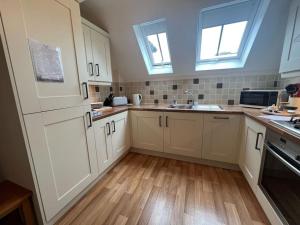 una cocina con armarios blancos y suelos y ventanas de madera. en Central Village flat, close to beach, en Milford on Sea
