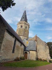 an old church with a steeple and a building at Sérendipity in Marquise