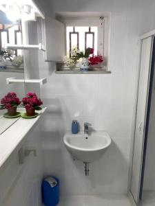 a white bathroom with a sink and a window at Green House Trecastagni in Trecastagni