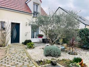 een wit huis met een tuin met een boom bij Maison chaleureuse centre Saran in Saran