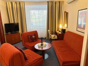 a living room with orange furniture and a television at Wellness Hotel Staré Město in Uherské Hradiště