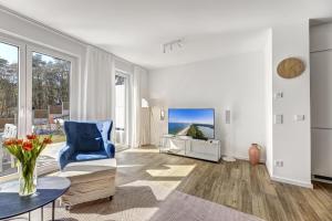 a living room with a blue chair and a tv at Ferienhaus "Süsterhüs" - Seeluft und Komfort in Loddin
