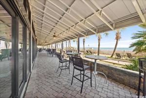 a patio with tables and chairs and the beach at Oceanfront Paradise/Waterpark/pools/lazyriver in Myrtle Beach