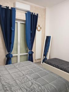 a bedroom with a bed and a window with blue curtains at Appartamento 50 mt dal mare in Lido di Ostia