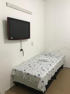 um quarto com uma cama e uma televisão de ecrã plano na parede em Pousada Linhares em João Pessoa