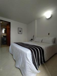um quarto com uma cama grande e um cobertor preto e branco em Tranquilo envigado em Envigado