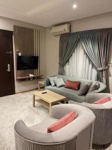 Verona فيرونا في الرياض: غرفة معيشة مع أريكة وكرسيين