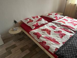 a bed with a red and white blanket with flowers on it at Gästehaus Aarninkstraße in Nordhorn