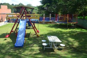 einen Spielplatz mit Rutsche und einem Tisch im Gras in der Unterkunft RECANTO MARIANE in Santo Antônio do Amparo