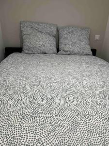 a bed with a black and white comforter and two pillows at Loiret Luxe Studio in Olivet