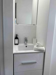 a white bathroom with a sink and a mirror at Loiret Luxe Studio in Olivet