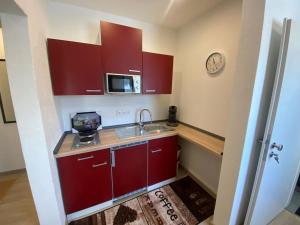 a kitchen with red cabinets and a sink and a clock at Ferienwohnung Bergruhe in Memmingen