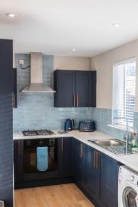 eine Küche mit blauen Schränken und einem Waschbecken in der Unterkunft 68 Glenwood Road in Ellesmere Port