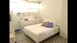 a bedroom with a white bed with a purple pillow at Bungalow 4 Binisafua in Binisafua