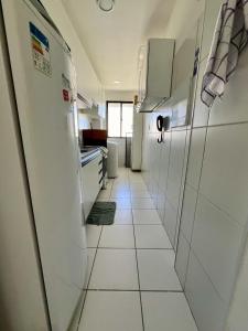 a kitchen with white cabinets and a white tile floor at Apto próximo à Fac. Pio X in Aracaju