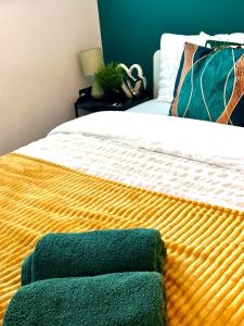 a bed with a green and yellow blanket on it at Beautiful Studio flat in Purley