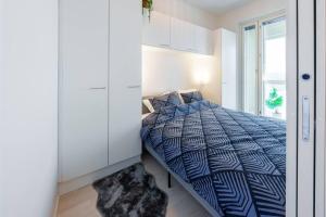 een slaapkamer met een bed met een blauw dekbed en een raam bij Cozy 1-bed super flat, 20 min to Helsinki/Airport in Vantaa