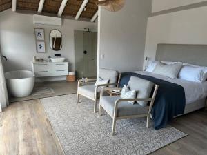 a bedroom with a bed and two chairs and a tub at Laid back luxury canal house in St Francis Bay