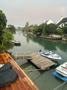 two boats are docked at a dock on a river at Laid back luxury canal house in St Francis Bay