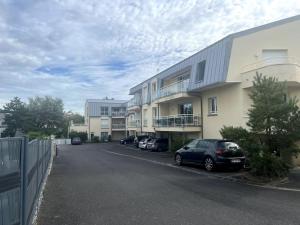 um parque de estacionamento com carros estacionados em frente a um edifício em Accès direct plage 100m em Jullouville-les-Pins