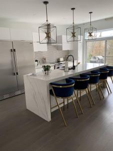 a kitchen with a white counter and blue bar stools at Unwind @ The Lakeside Getaway Your Oasis in Nature in Val des Monts