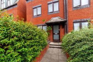 a brick building with a door and some bushes at Hidden treasure 2 BR ground floor apt, Brentford in Brentford