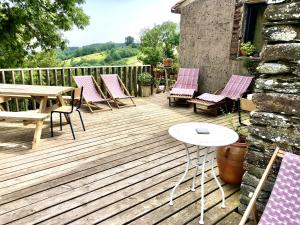 una terraza de madera con sillas y una mesa. en Grange spacieuse et élégante, en Dourgne