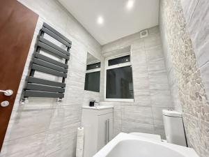 La salle de bains est pourvue de toilettes blanches et d'une fenêtre. dans l'établissement Perfect Place For Contractors & Family Stays, à Luton