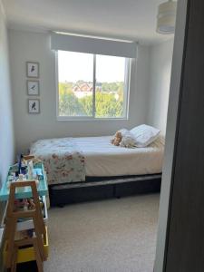 um quarto com um cão deitado numa cama com uma janela em Dpto Vita3 2D2B Puerto Varas em Puerto Varas