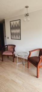 duas cadeiras e uma mesa de vidro num quarto em Dpto Vita3 2D2B Puerto Varas em Puerto Varas
