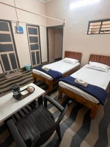 a room with two beds and a table and a chair at Vintage Walls Homestay in Hampi