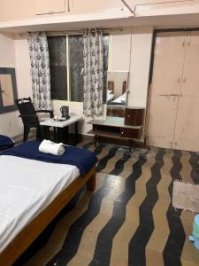 1 dormitorio con cama, escritorio y espejo en Vintage Walls Homestay, en Hampi