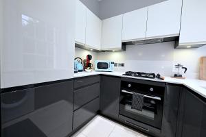 a kitchen with white cabinets and a black oven at STUNNING 4 BEDROOM FLAT IN REGENT'S PARK - ABBEY Rd in London