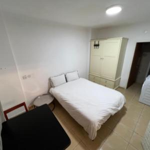 a small bedroom with a white bed and a chair at Happy Home in Eilat
