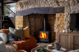 a dog sitting on a couch in front of a fireplace at Bourton Newly Remodeled Scandi Chic Authentic Charm & Character in Bourton on the Water