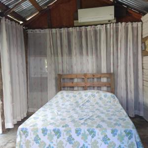 a bedroom with a bed with curtains and a air conditioner at La Loma Camping in Higuey