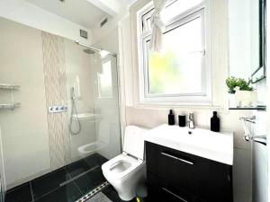 a bathroom with a toilet and a sink and a window at Spacious 2-Bed House 20 mins from Central London in London